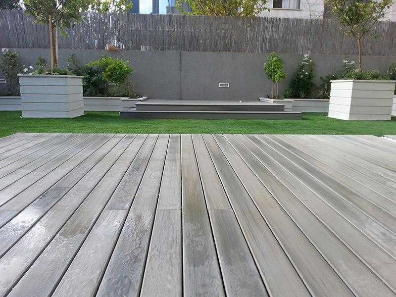 דק עץ בשילוב דשא סינטתי במת עץ מוגבהת ואדניות מובנות בגינת חצר