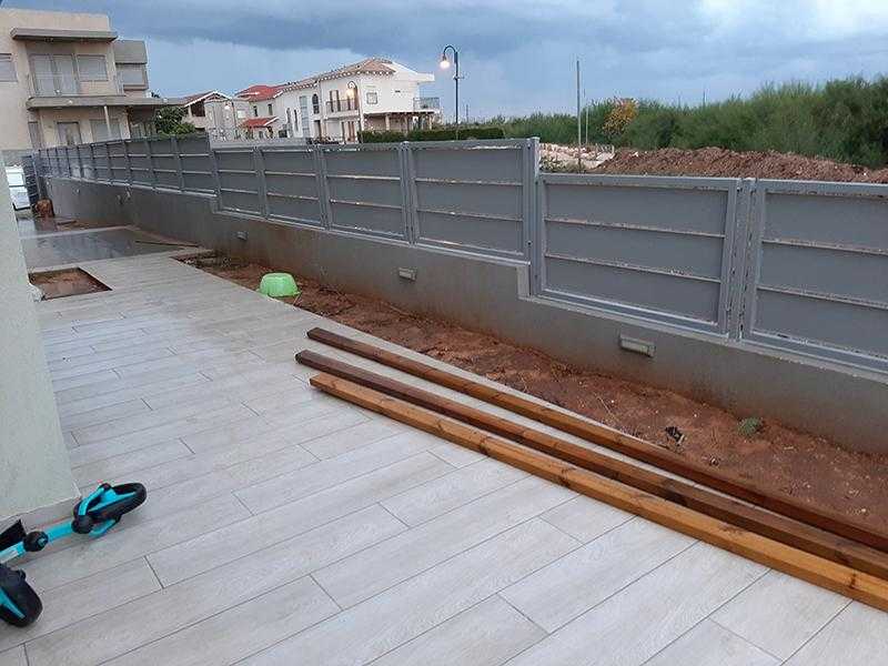 עיצוב גינת חצר משלבת עץ, אבן ומתכת סביב בית במרכז הארץ