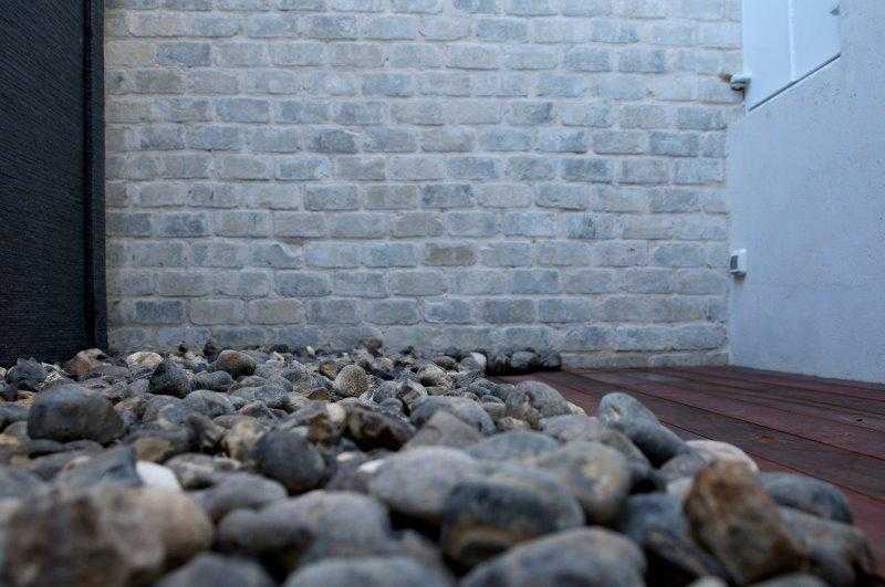 פריט מגינת חצר מעוצבת - שילוב בין דק עץ, חיפוי אבן על הקיר וחלוקי אבן על האדמה