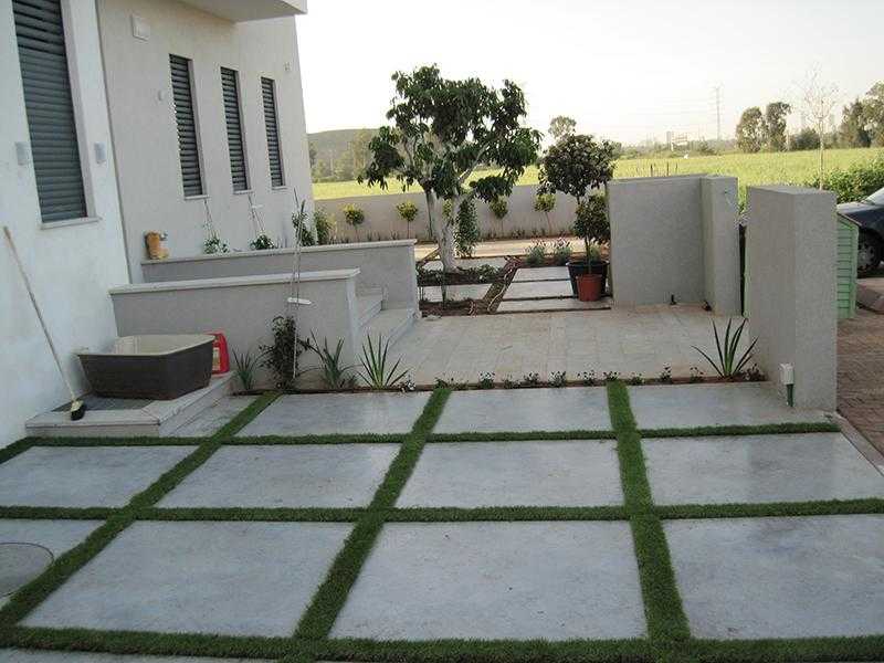 משטח בגינת חצר משבץ אדמה עם לוחות אבן רחבה, דשא וצמחייה מעורבת