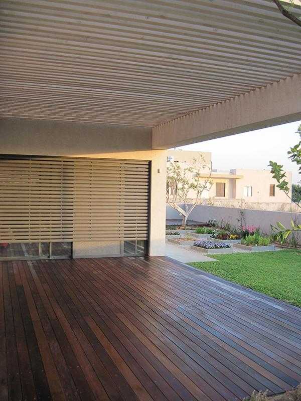 פרגולת עץ בחצר הבית עם גינה בשילוב דשא דק עץ אדניות מוגבהות