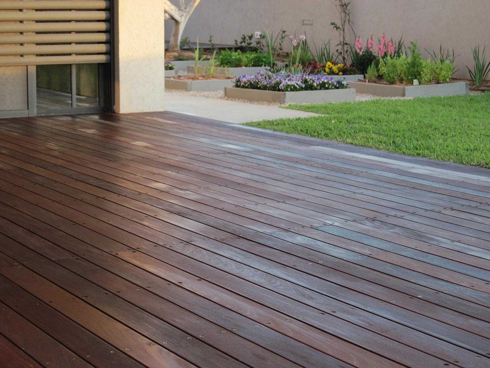 דק עץ בגינת חצר בשילוב דשא וחצץ עם אדניות מוגבהות