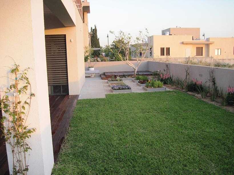 רצפת דק עץ ודשא בגינת חצר בשילוב אדניות מוגבהות