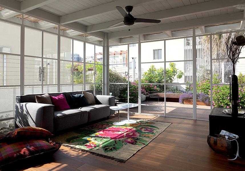 פרגולת עץ לבנה עם סגירת חלונות זכוכית בחצר הבית