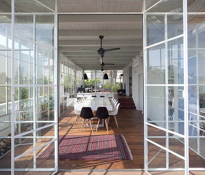 פרגולת עץ לבנה עם סגירת חלונות זכוכית בחצר הבית