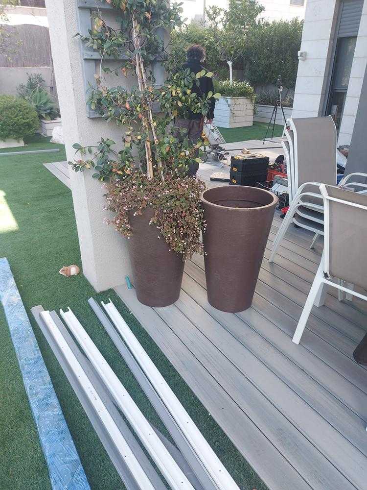 שילוב של משטח דק דשא סינטתי ועציצים מעוצבים בגינת חצר