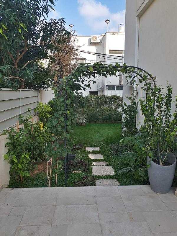 גינת חצר צמחייה מעורבת עם שילוב עציצים אבני מדרך דשא וסככה למטפסים