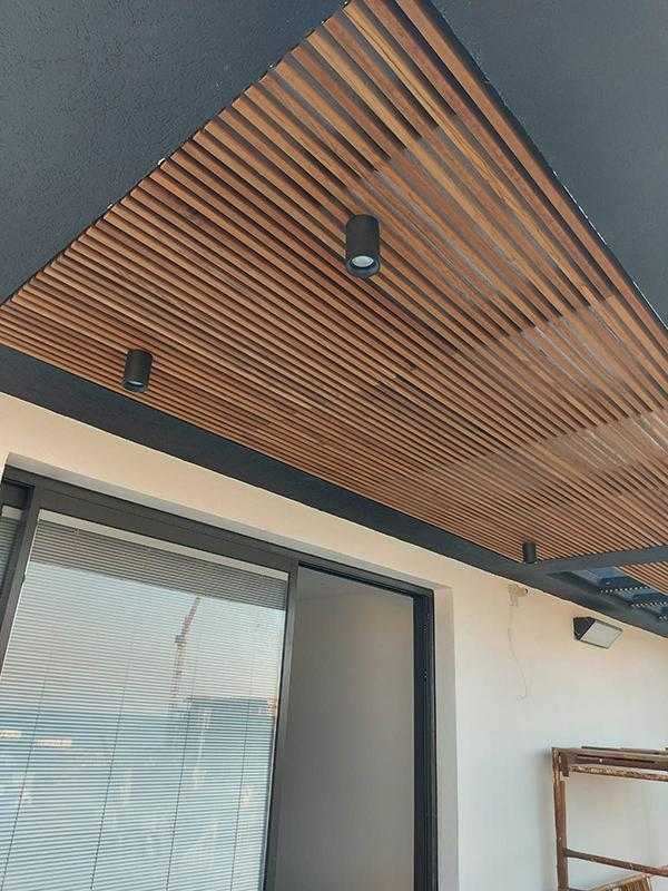 פרגולת עץ ומתכת בשילוב גופי תאורה במרפסת