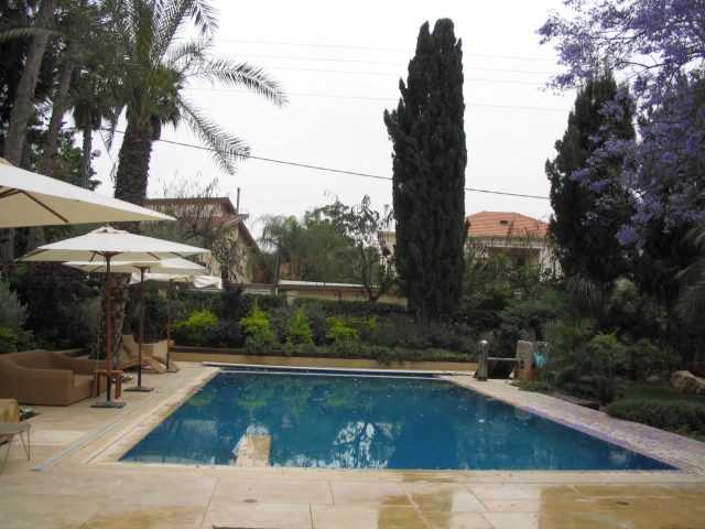 עיצוב גינה סביב בריכה עם פינת ישיבה ושמשיות